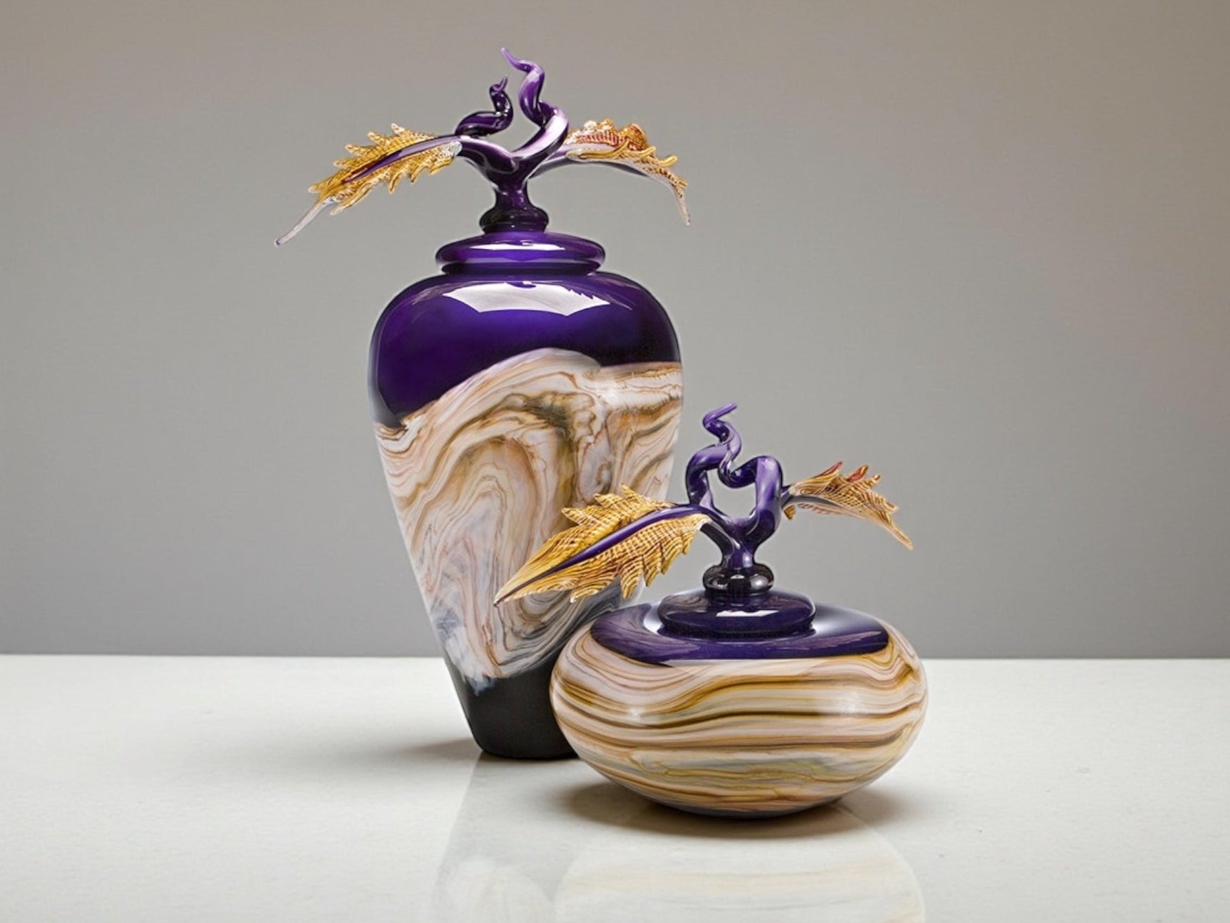 Decorative glass bottles with artistic designs on a neutral background